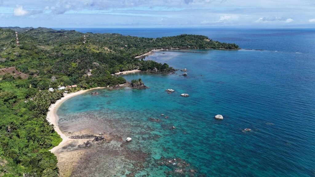 Luftaufnahme der Bucht bei der Natiora Green Lodge auf Sainte Marie mit Sandstrand und türkisfarbenem Wasser.