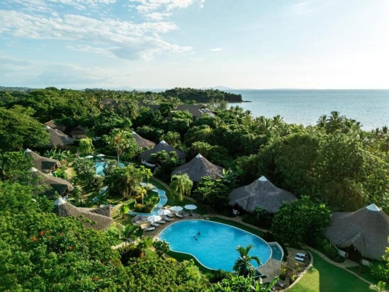 Luftaufnahme der Loharano Lodge auf Nosy Be mit Pools, Bungalows im tropischen Garten und Blick auf das Meer.